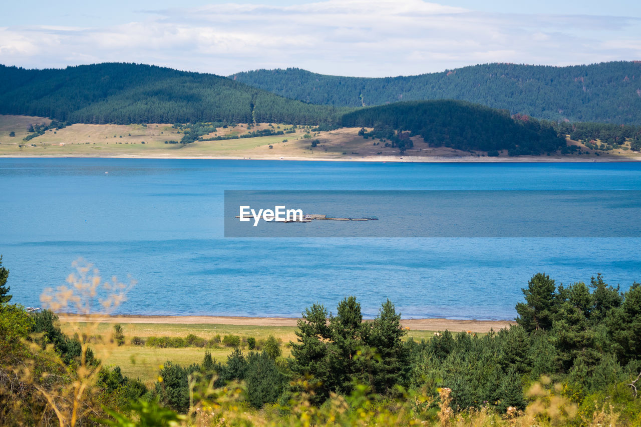 Scenic view of sea and mountains against sky