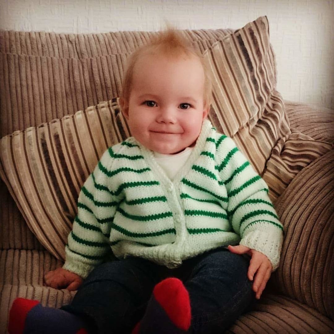 PORTRAIT OF CUTE BABY GIRL SITTING ON SOFA