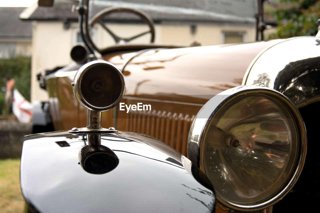 CLOSE-UP OF VINTAGE CAR ON CITY