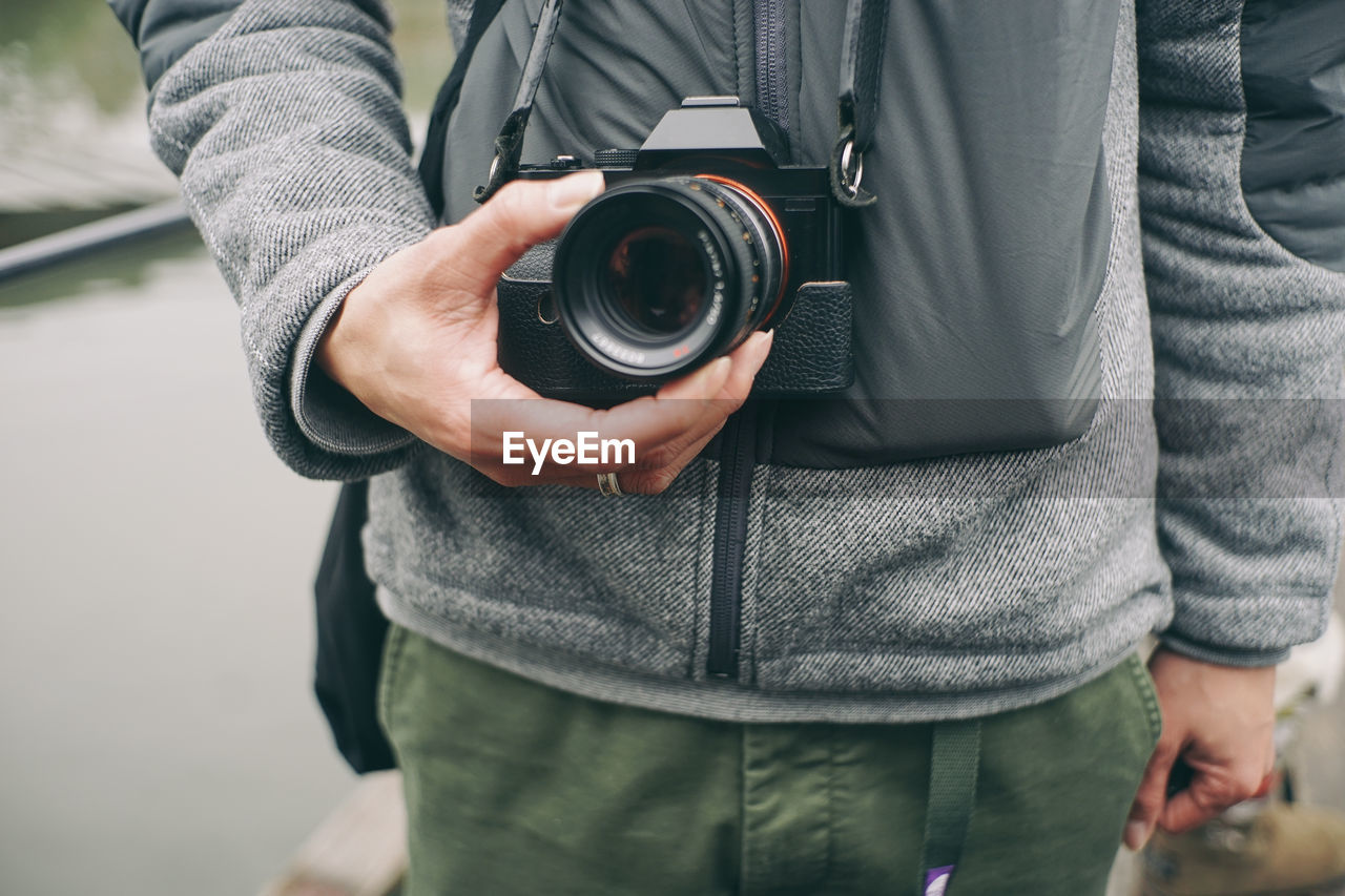 Midsection of man holding analog camera