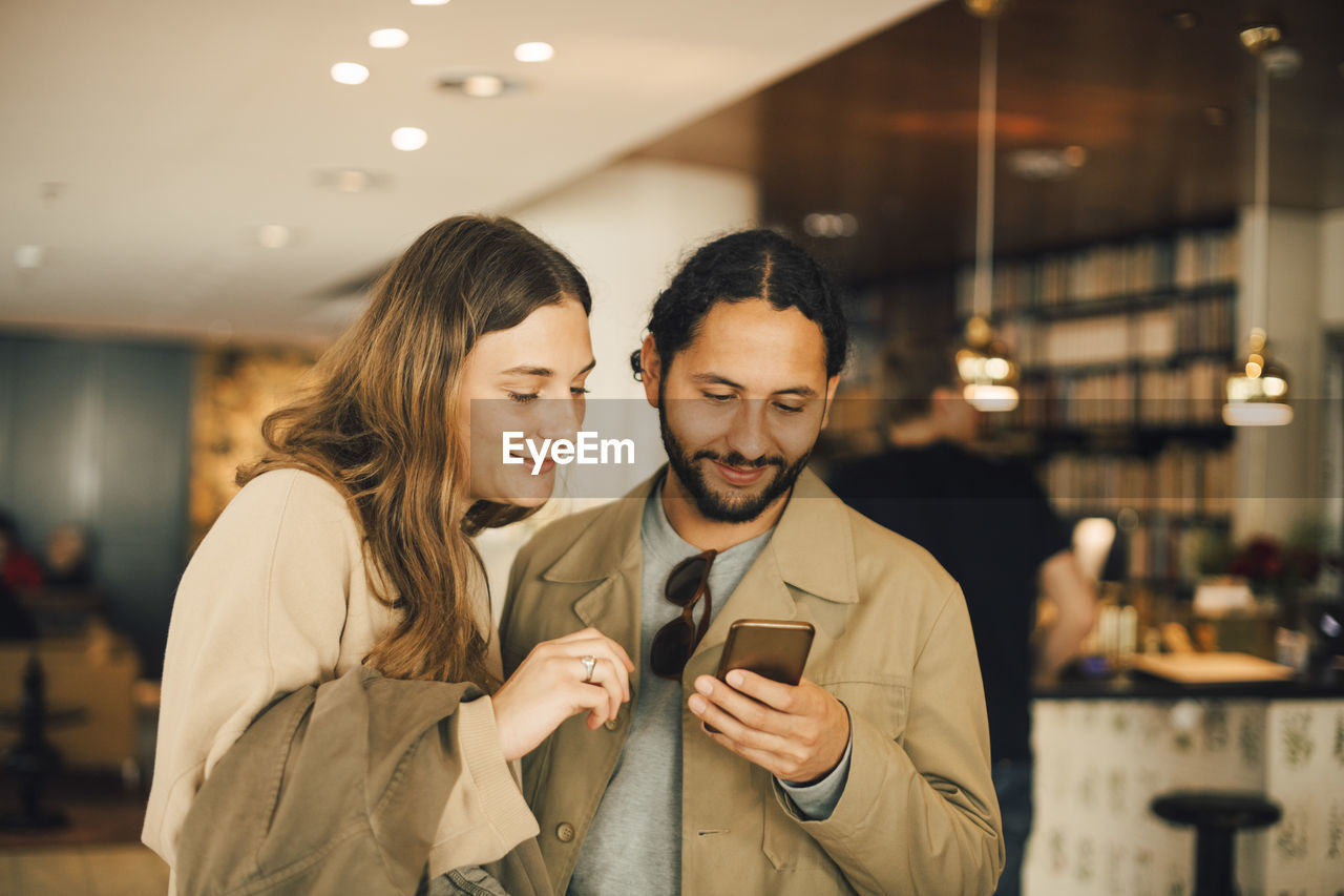 Couple using smart phone while standing in hotel