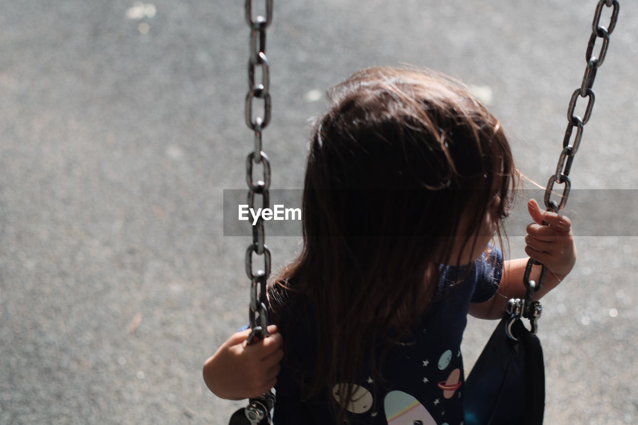 High angle view of girl playing on swing at playground