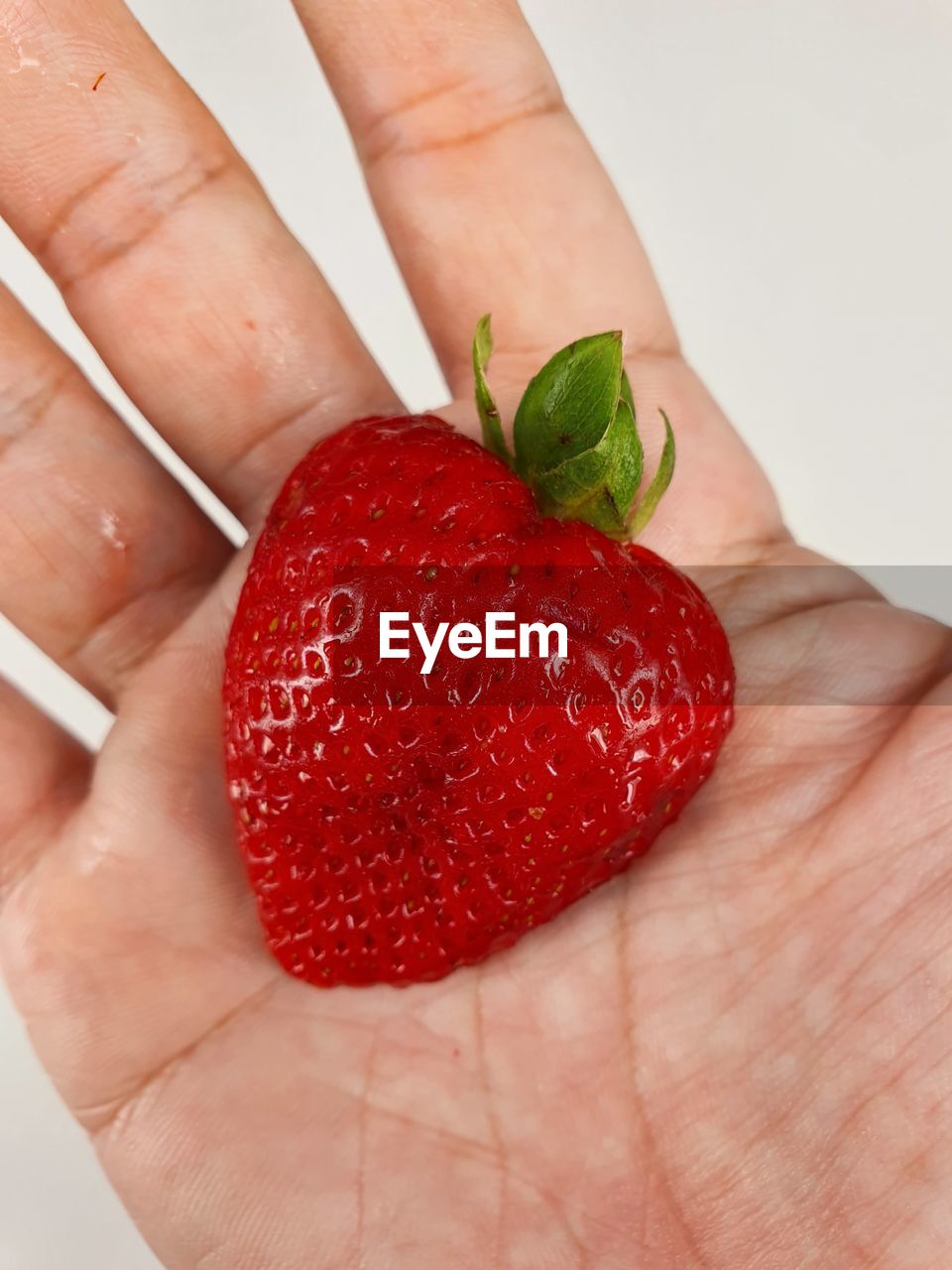 CLOSE-UP OF HAND HOLDING STRAWBERRY WITH STRAWBERRIES