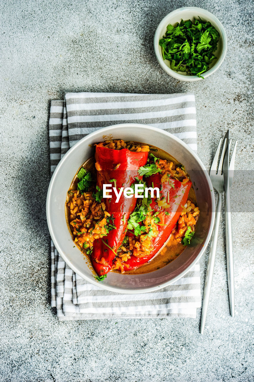 From above stuffed bell peppers stewed in stone pan with tomato sauce