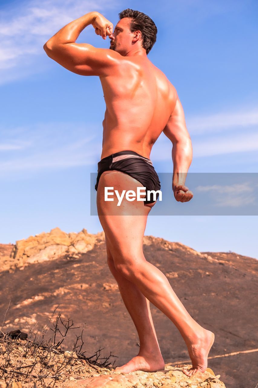 LOW ANGLE VIEW OF SHIRTLESS MAN IN DESERT
