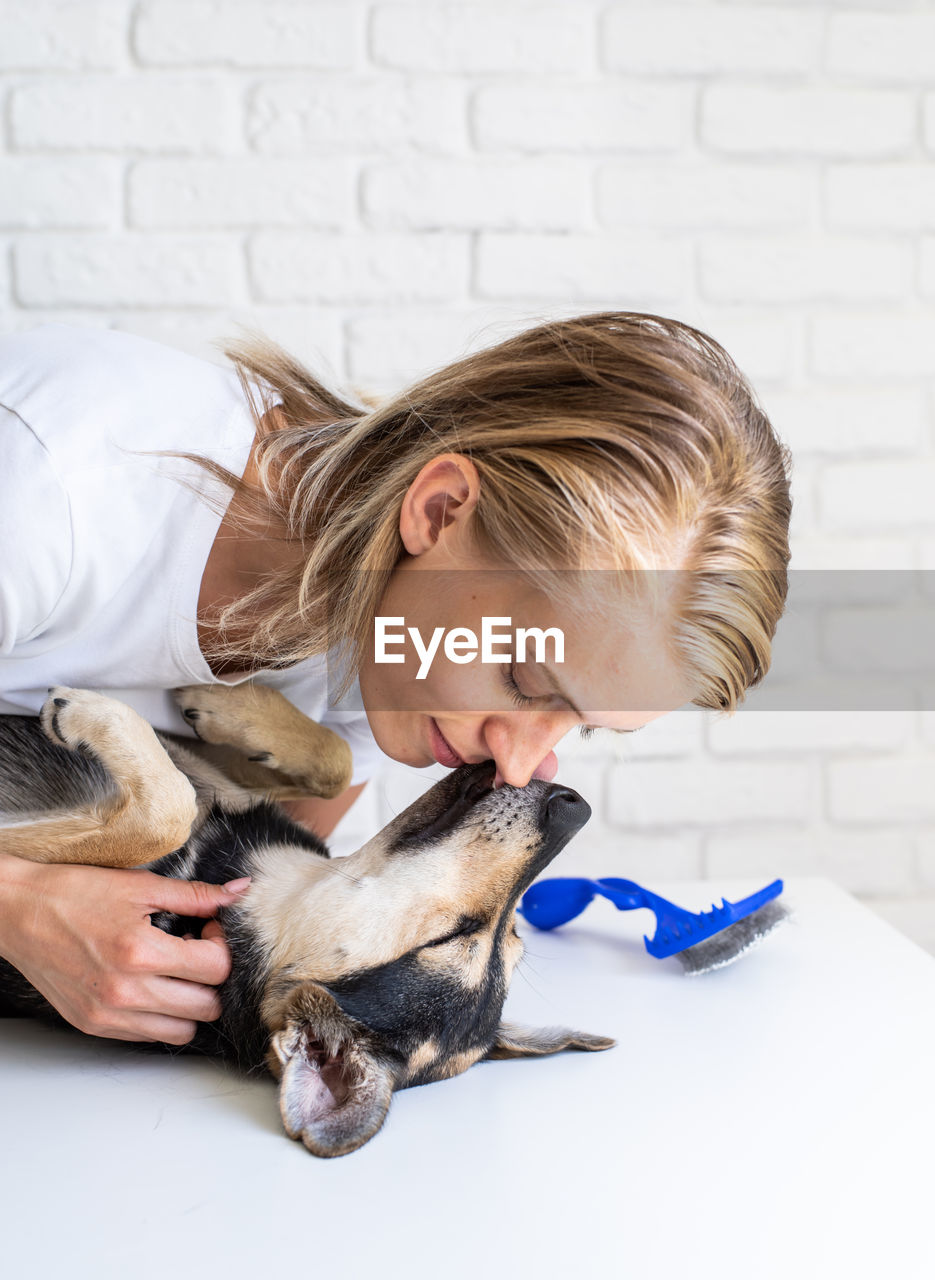 Woman with dog against wall