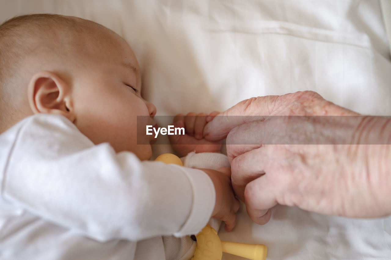 Cropped wrinkled hand touching baby at home