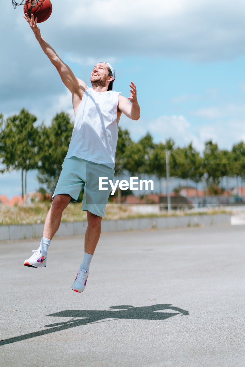 Full length of man with arms raised against sky