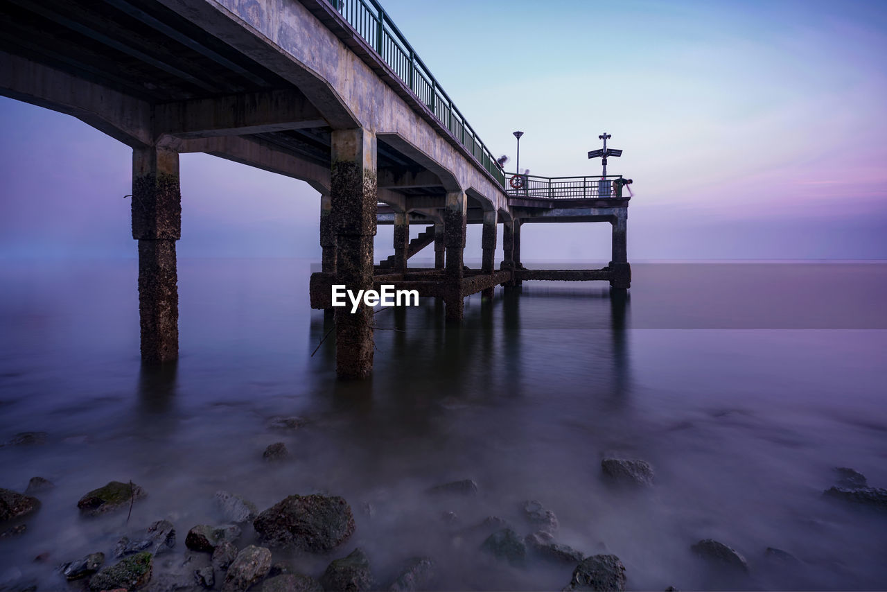 Pier over sea against sky during sunset