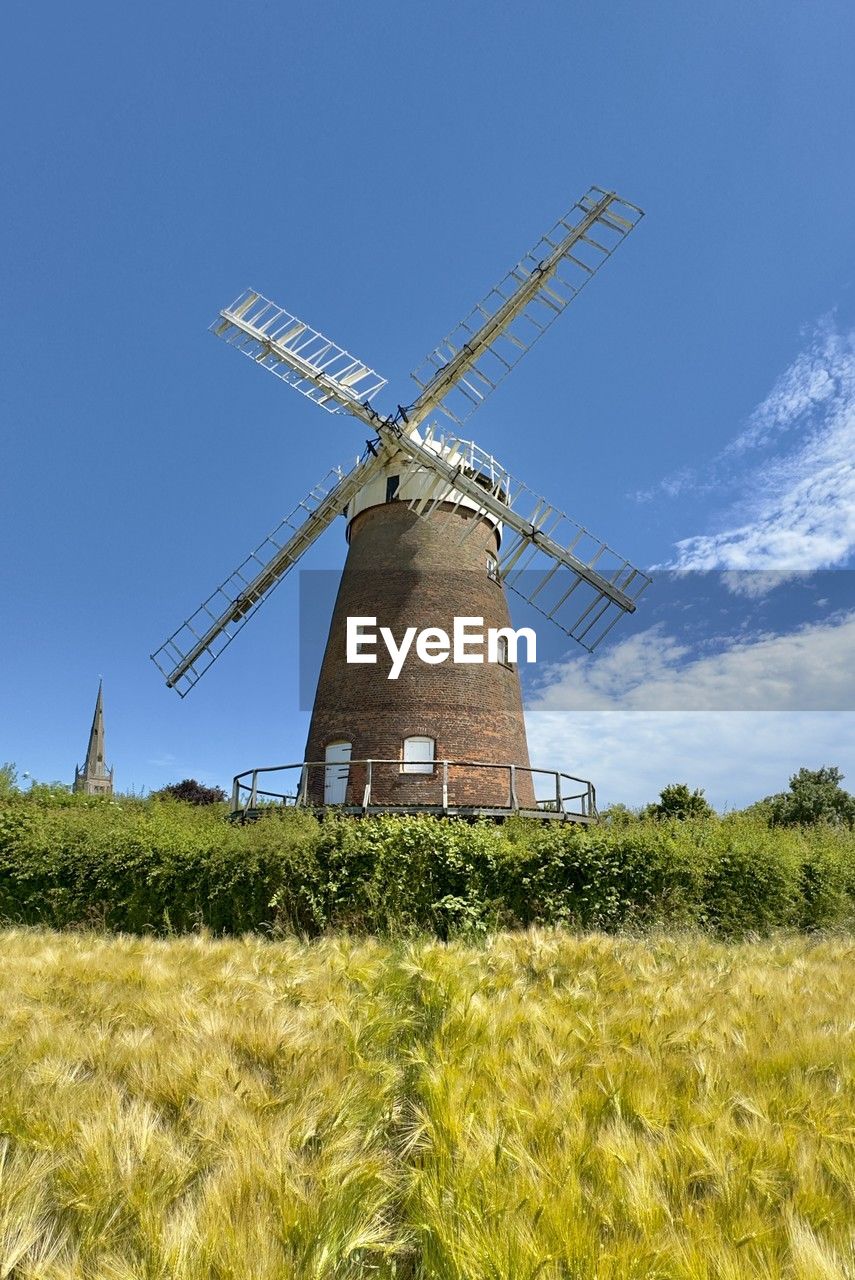 low angle view of windmills on field against clear blue sky