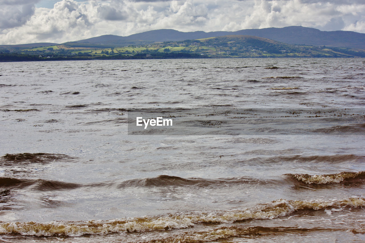 SCENIC VIEW OF SEA AGAINST MOUNTAIN RANGE