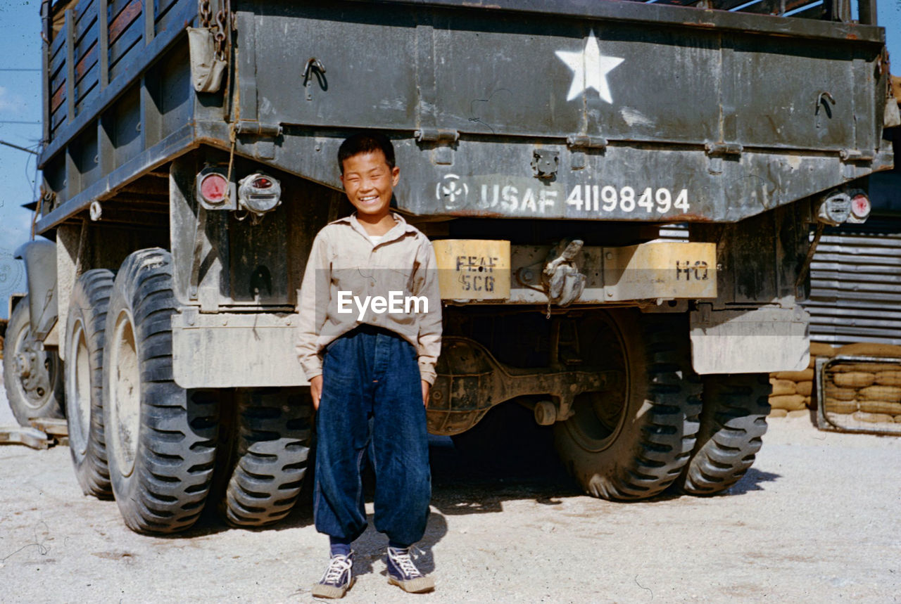 PORTRAIT OF A SMILING YOUNG MAN STANDING ON CART