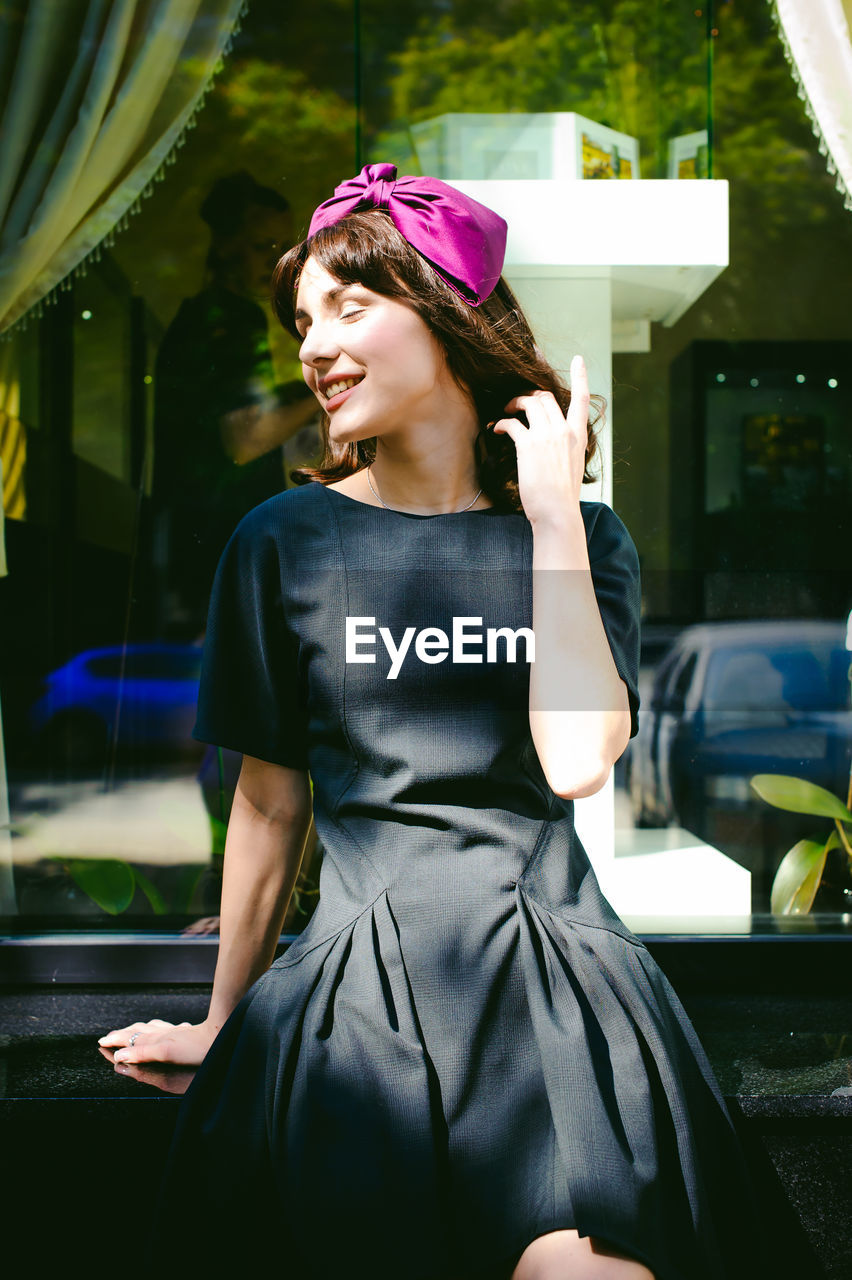 Beautiful young woman sitting by glass window