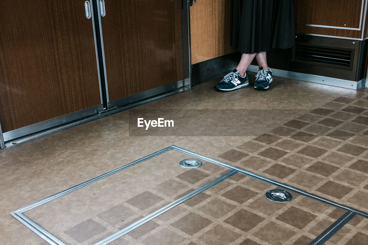 WOMAN STANDING ON TILED FLOOR WITH SHADOW