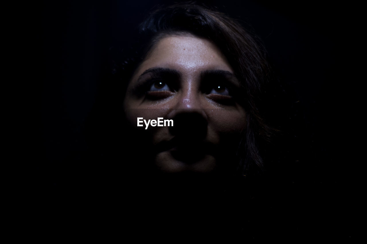 Close-up of young woman against black background