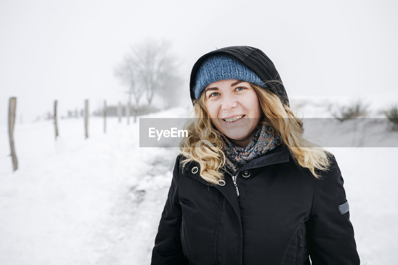 Blond woman standing on snow during vacations