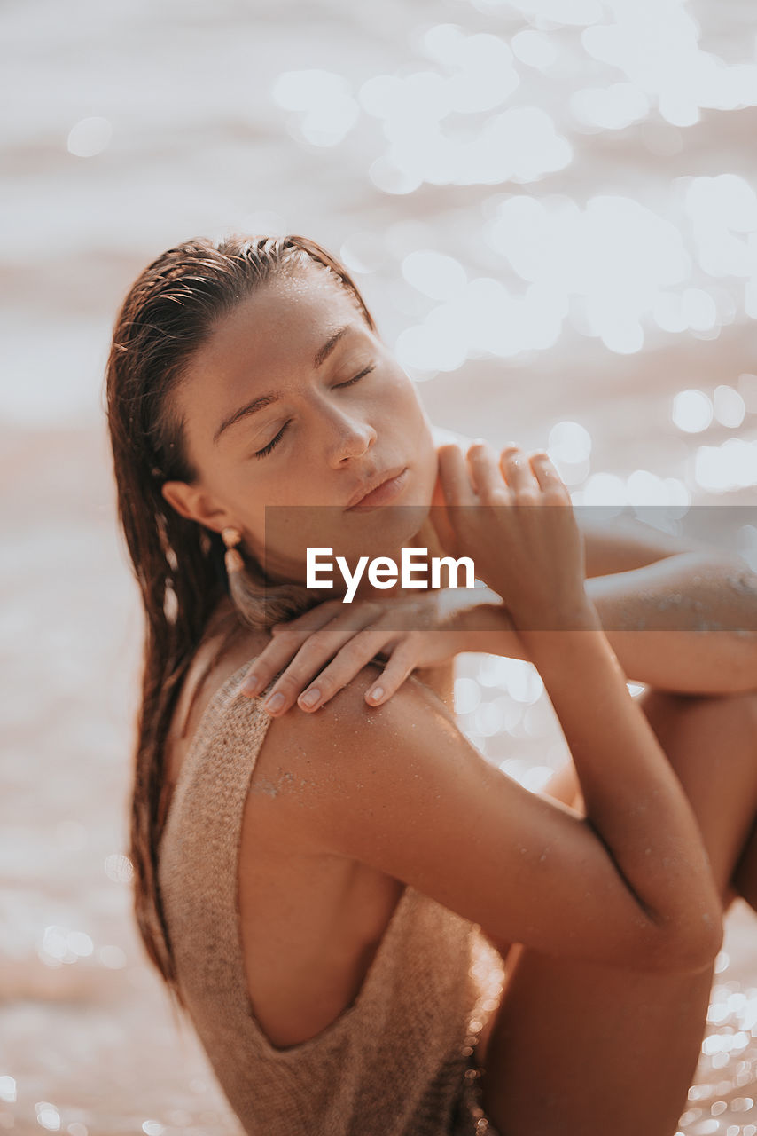 Side view of young woman sitting at beach