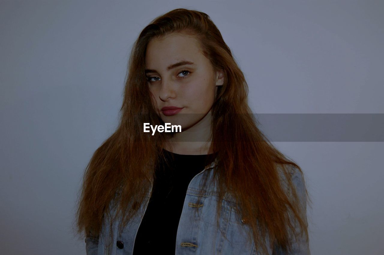 PORTRAIT OF YOUNG WOMAN AGAINST GRAY BACKGROUND