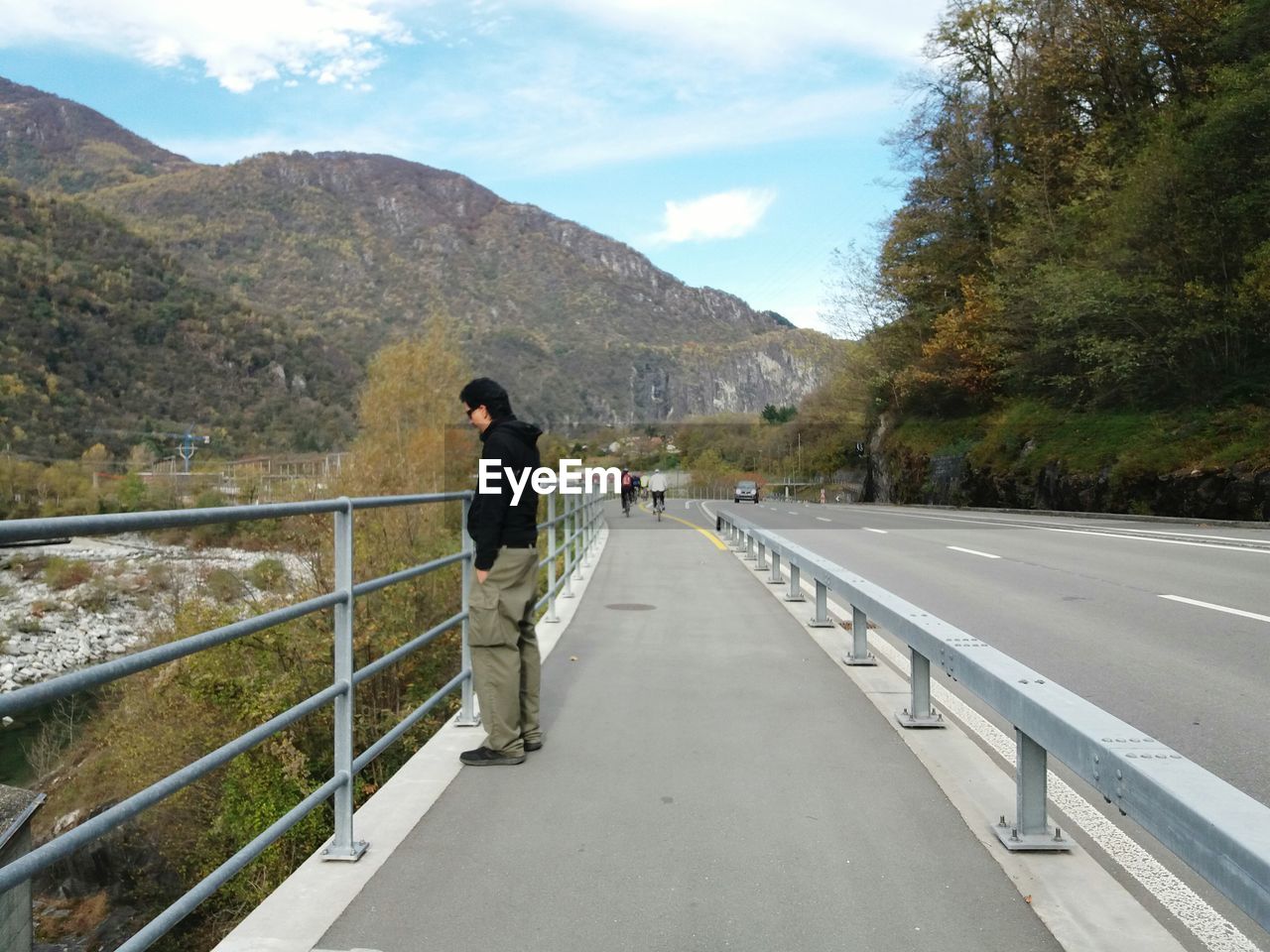 Side view of man standing on bridge against mountains