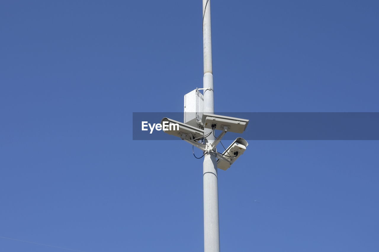 Low angle view of security camera on pole against sky