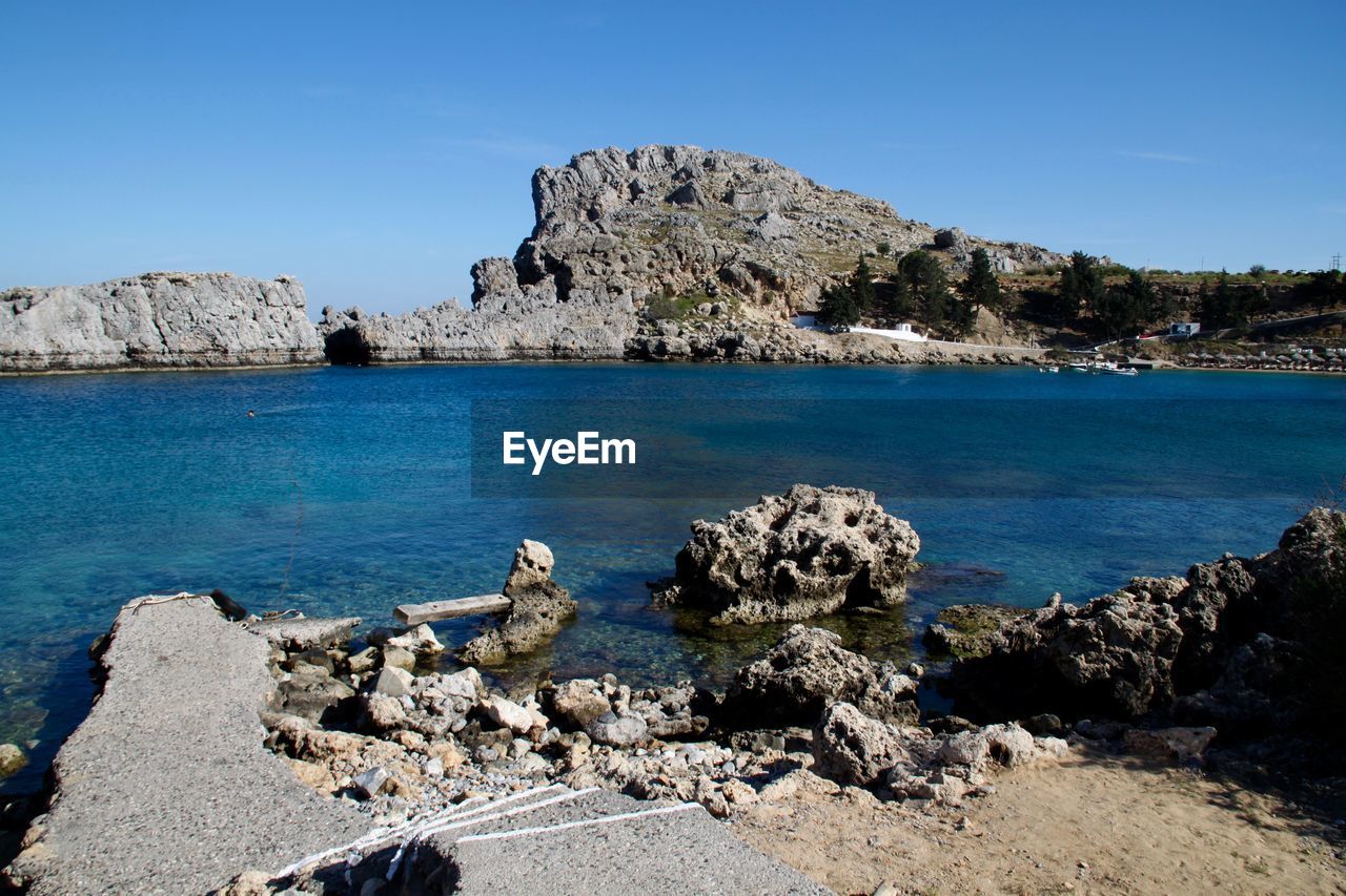 ROCK FORMATIONS IN SEA AGAINST CLEAR BLUE SKY