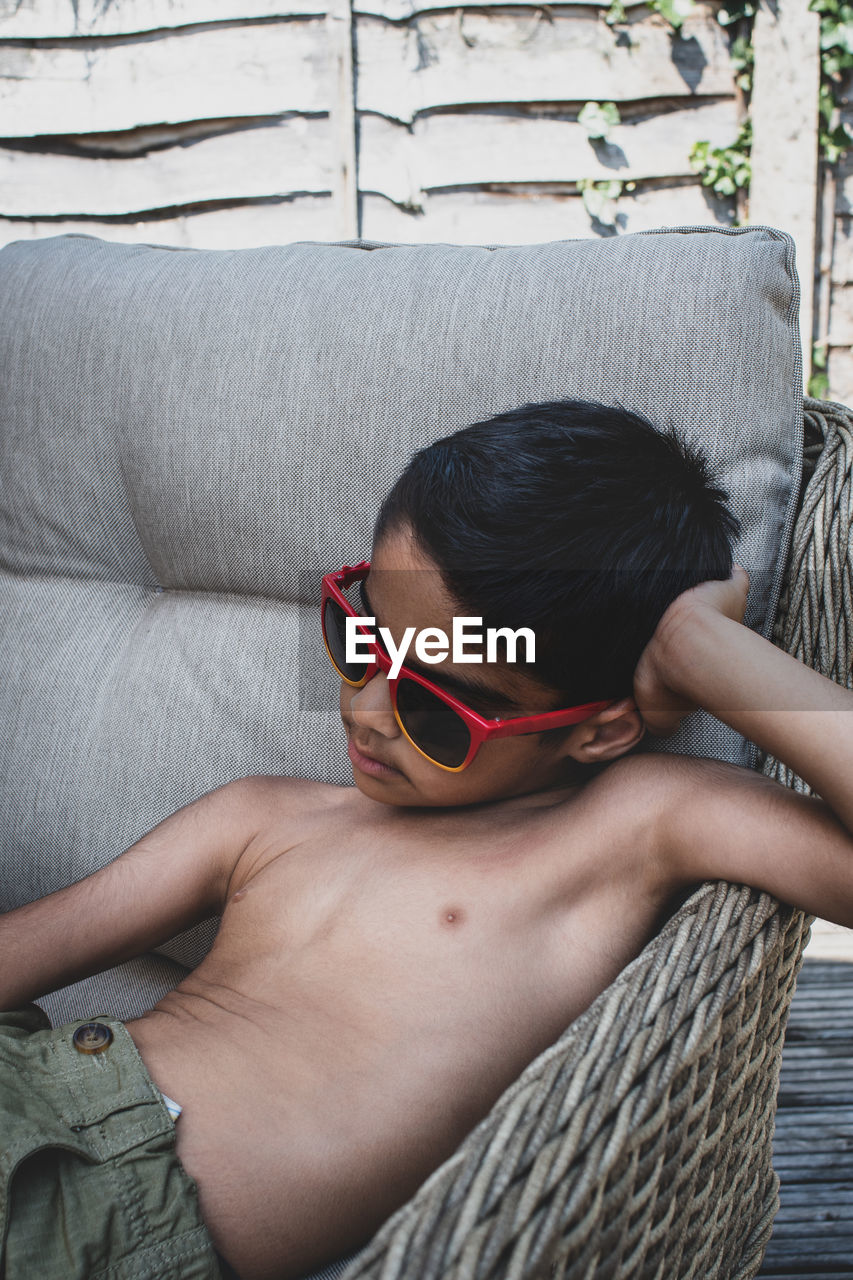 MIDSECTION OF BOY SITTING ON SUNGLASSES