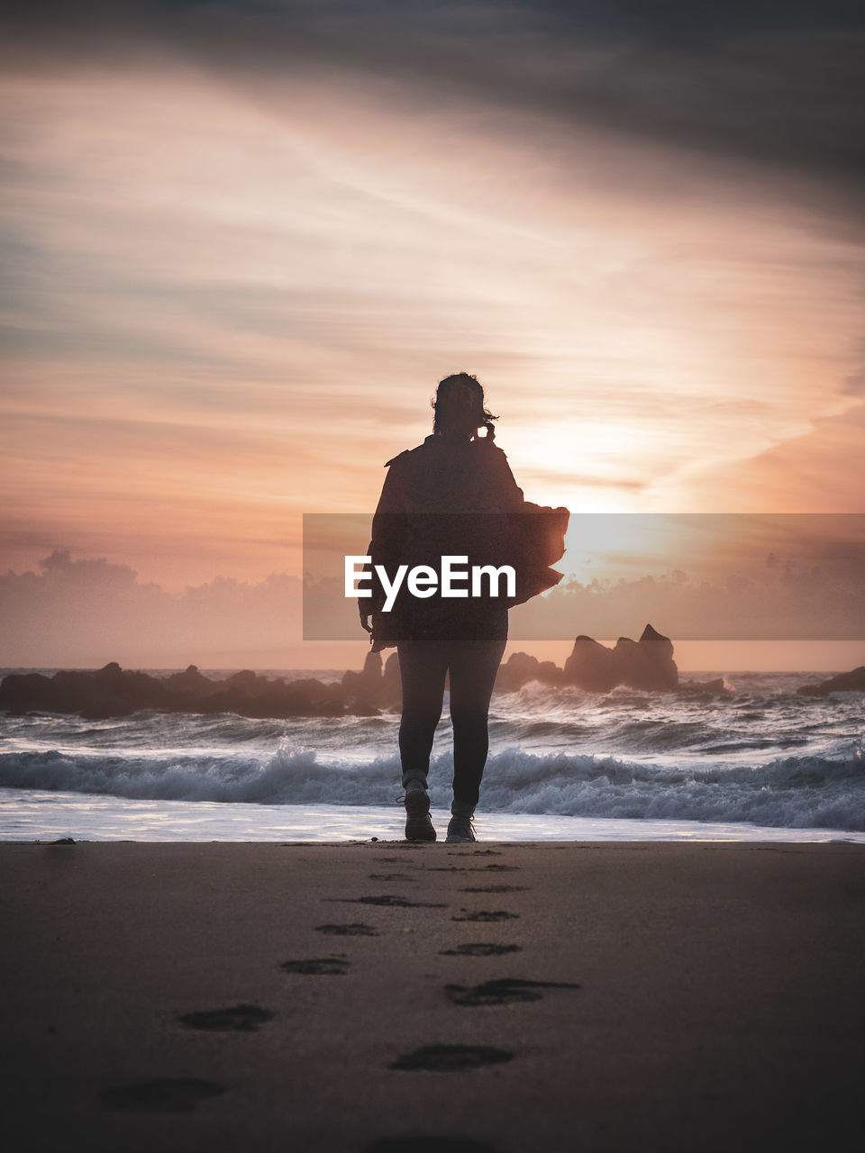 Silhouette man standing on beach against sky during sunset