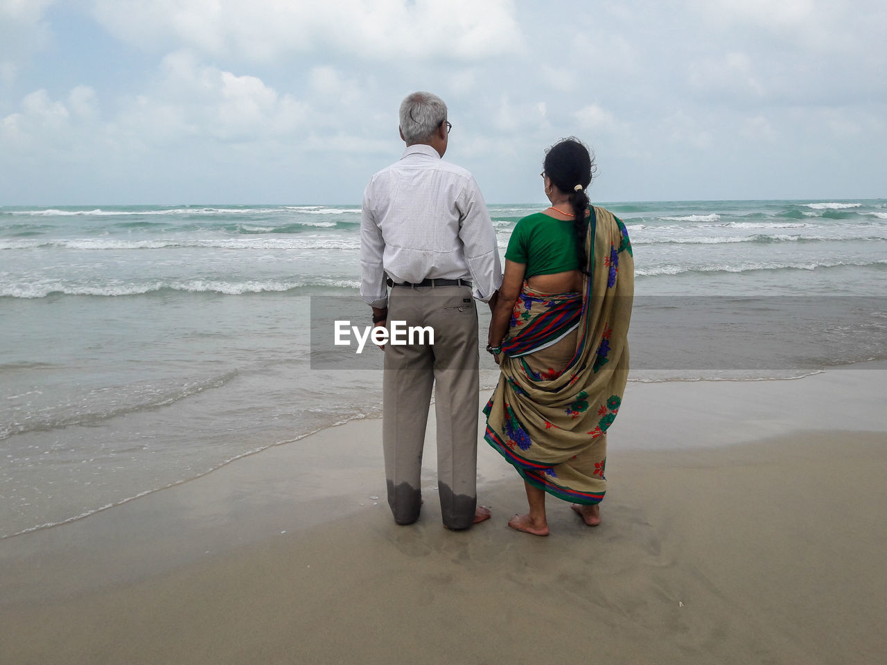 Rear view of men on beach against sky