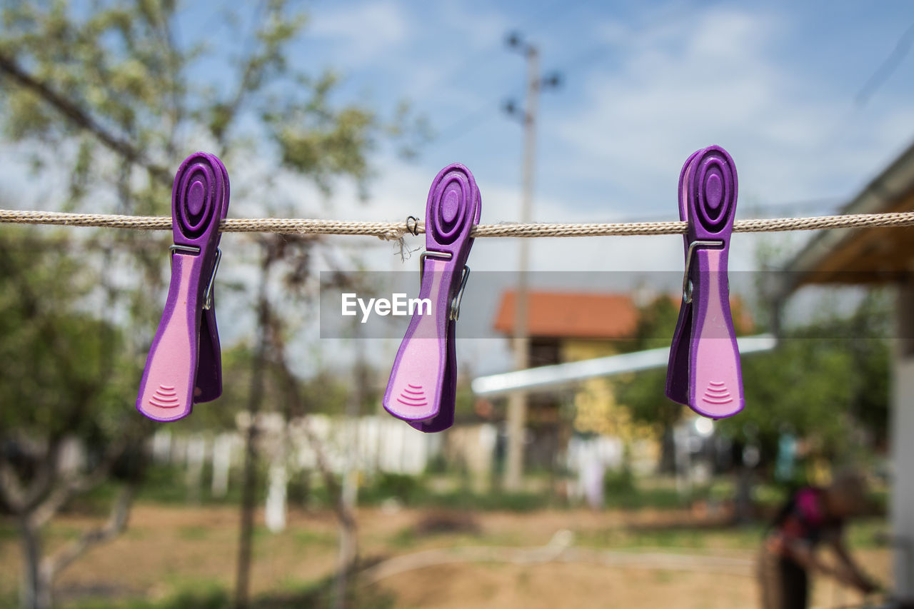 CLOSE-UP OF CLOTHESPINS HANGING ON ROPE