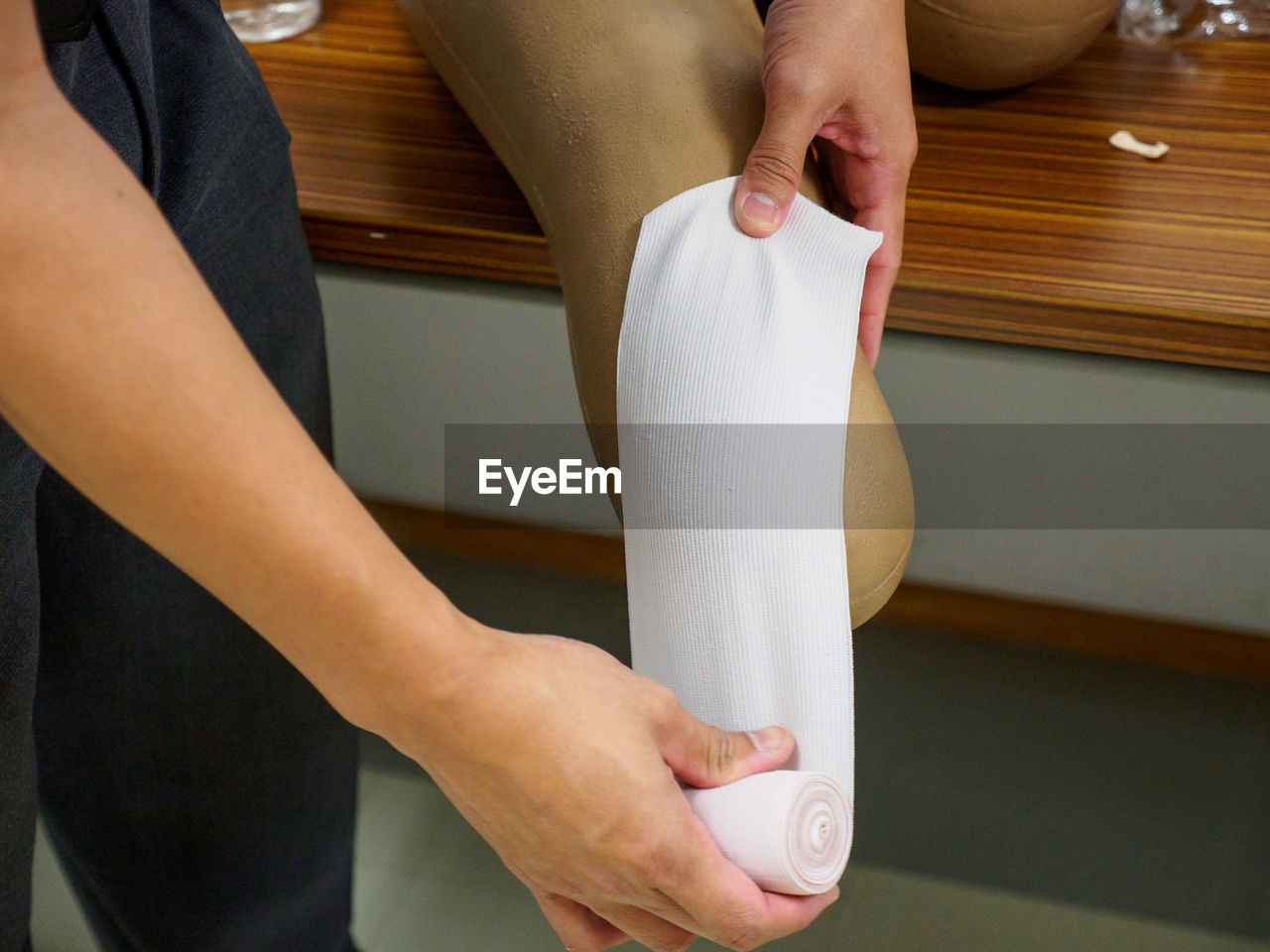 A doctor preparing to stump bandage a below-knee amputation patient using elastic roll gauze. 