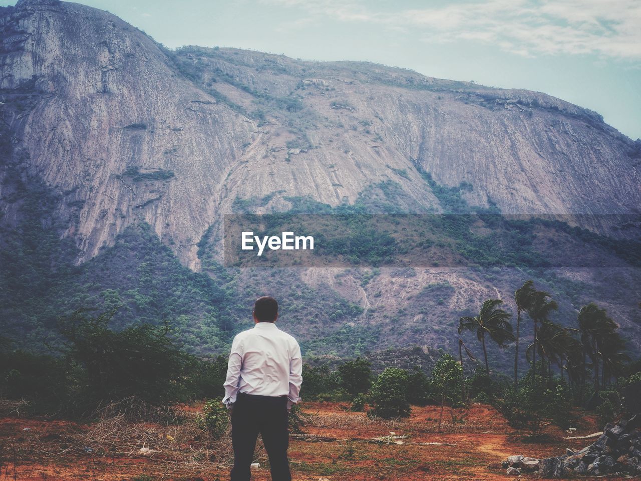 REAR VIEW OF MAN LOOKING AT MOUNTAIN