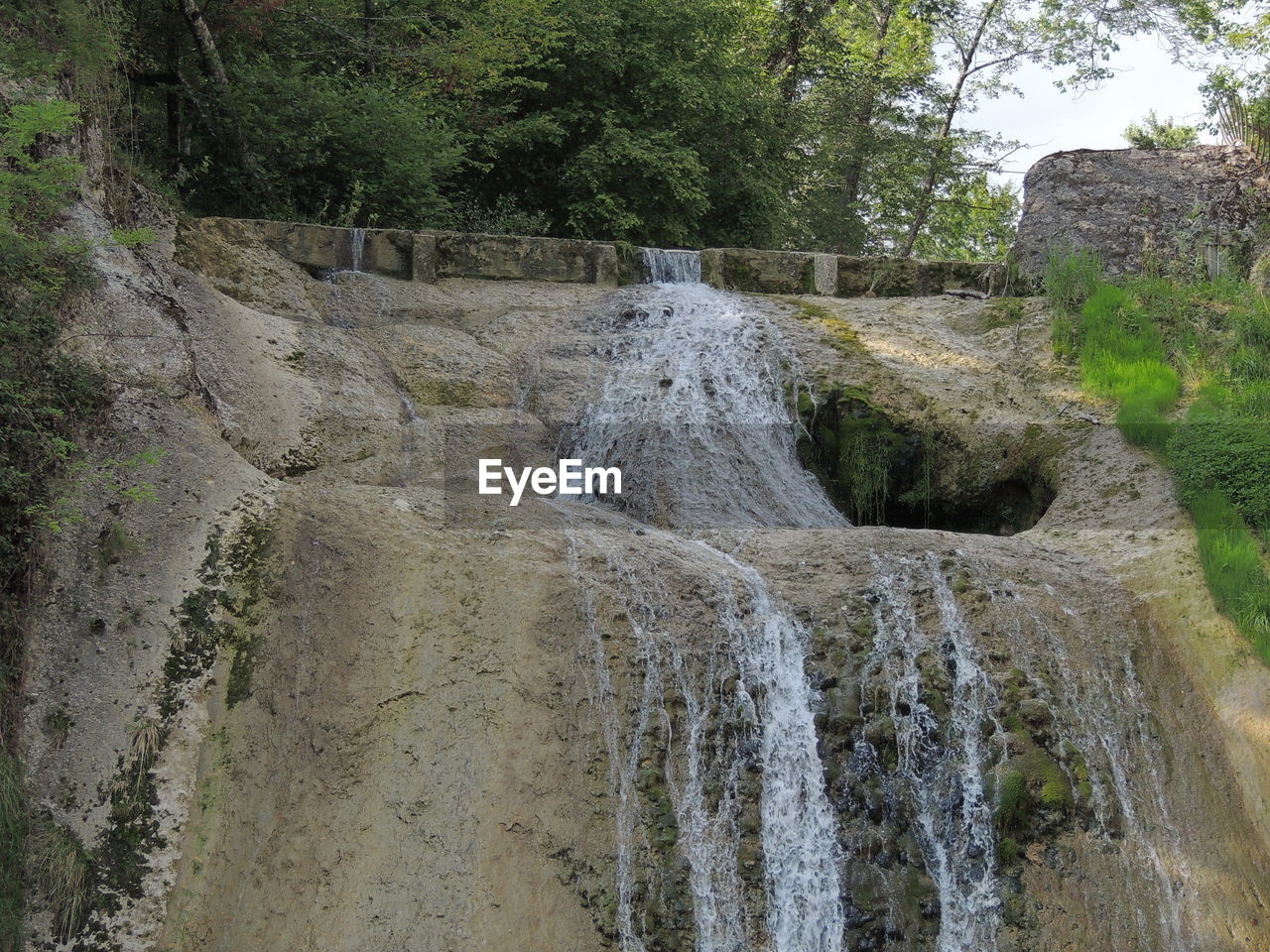 VIEW OF WATERFALL IN FOREST AGAINST SKY