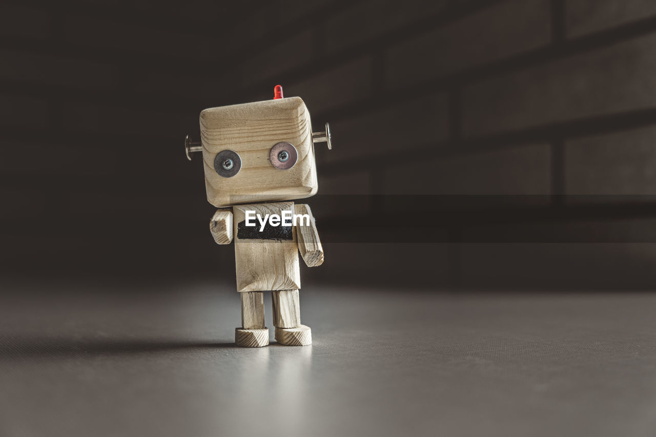 Lonely wooden android robot in a dark place is pointing at you. loneliness concept