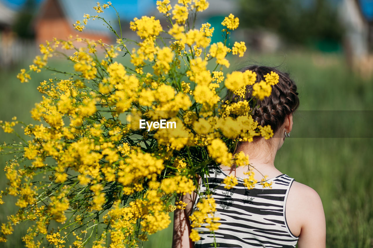 Low section of girl standing on yellow flowering plants