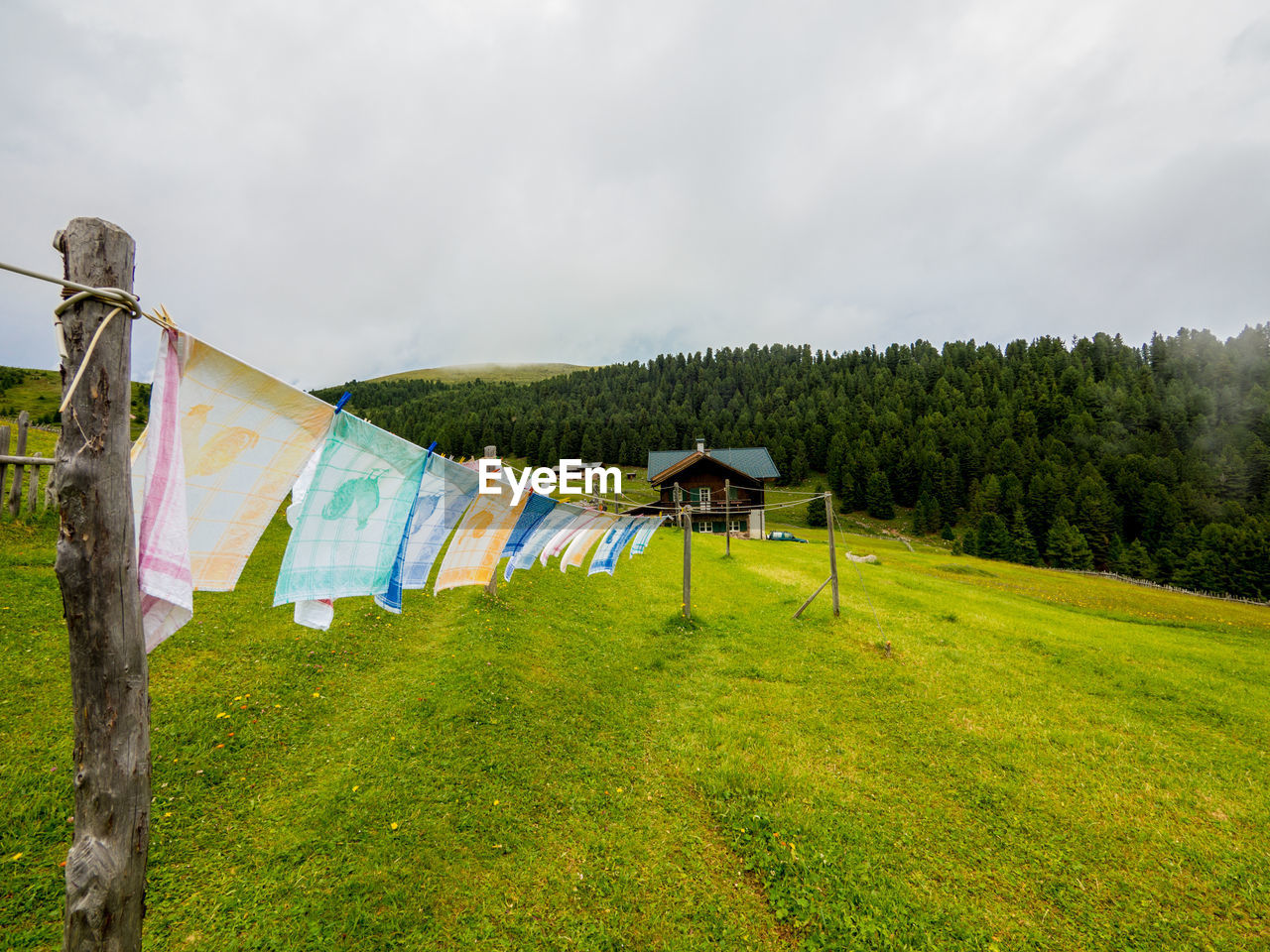 sky, plant, grass, environment, nature, rural area, cloud, meadow, landscape, land, no people, green, clothesline, laundry, field, tranquility, hanging, multi colored, drying, tree, scenics - nature, day, beauty in nature, rural scene, clothing, wind, outdoors, plain, textile, mountain, tranquil scene, travel, flag, non-urban scene, overcast, travel destinations, agriculture