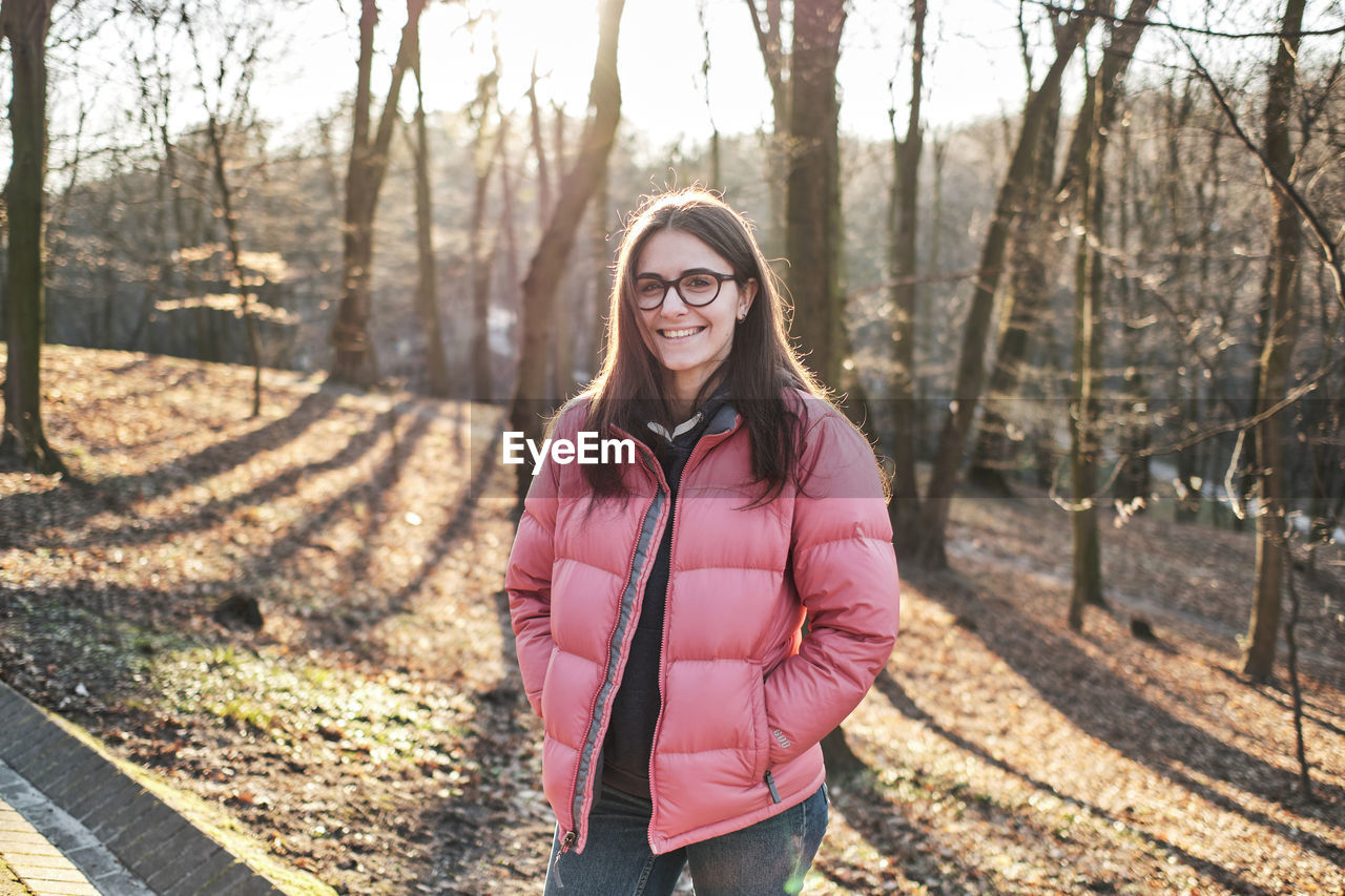 Happy young girl in glasses wearing a pink jacket and jeans