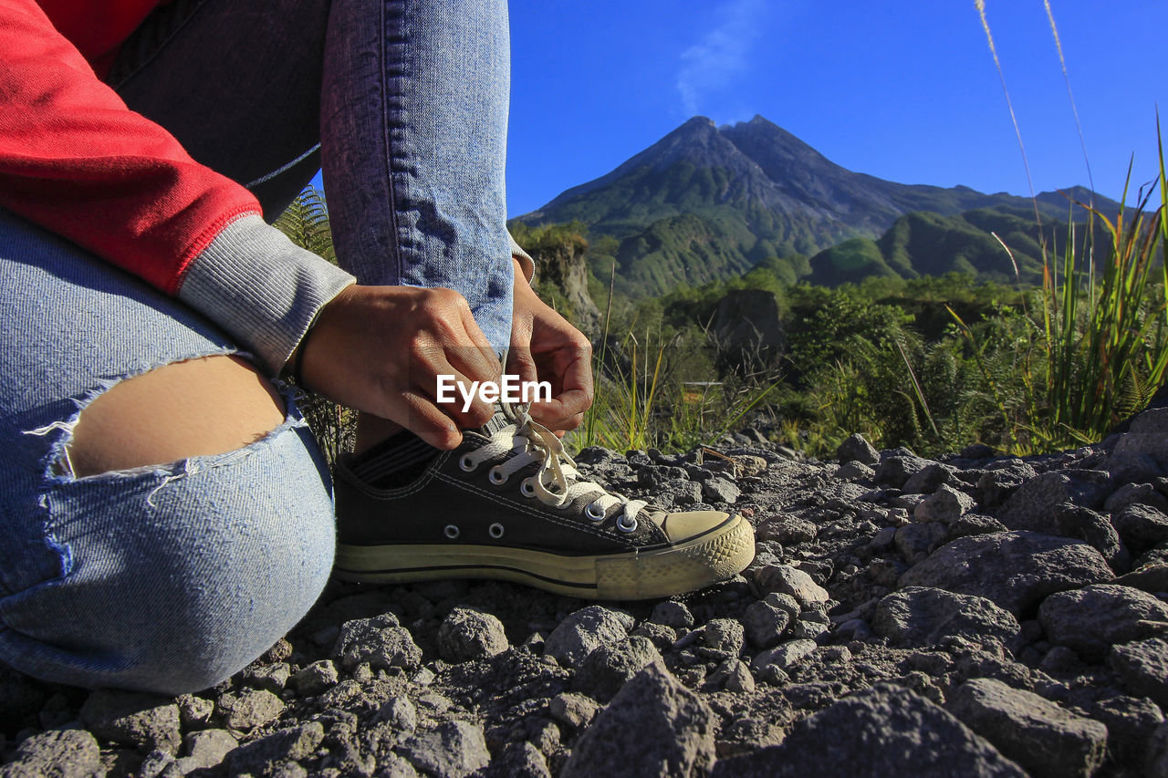 Low section of woman tying shoelace on land