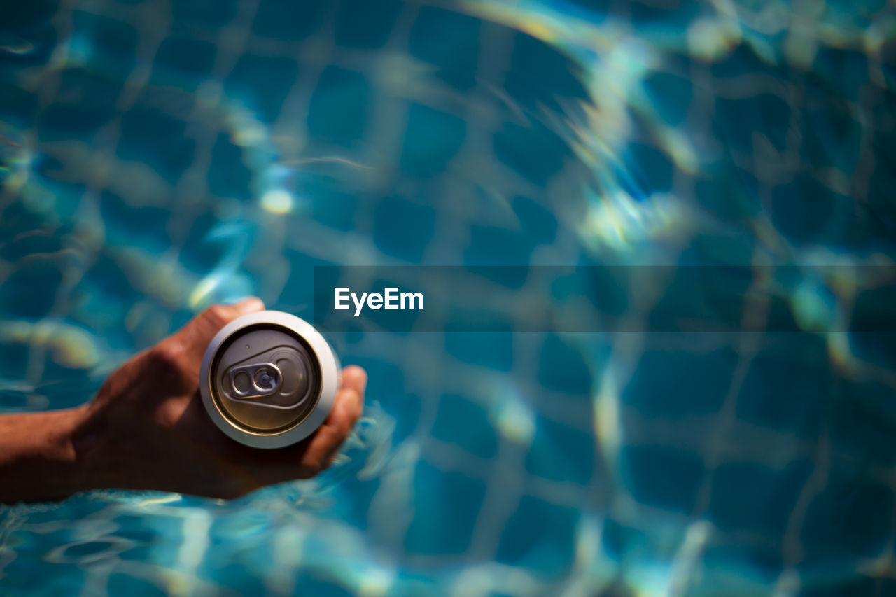 Selective focus white beer can in hand. man is soaking in the pool with an open beer can relax