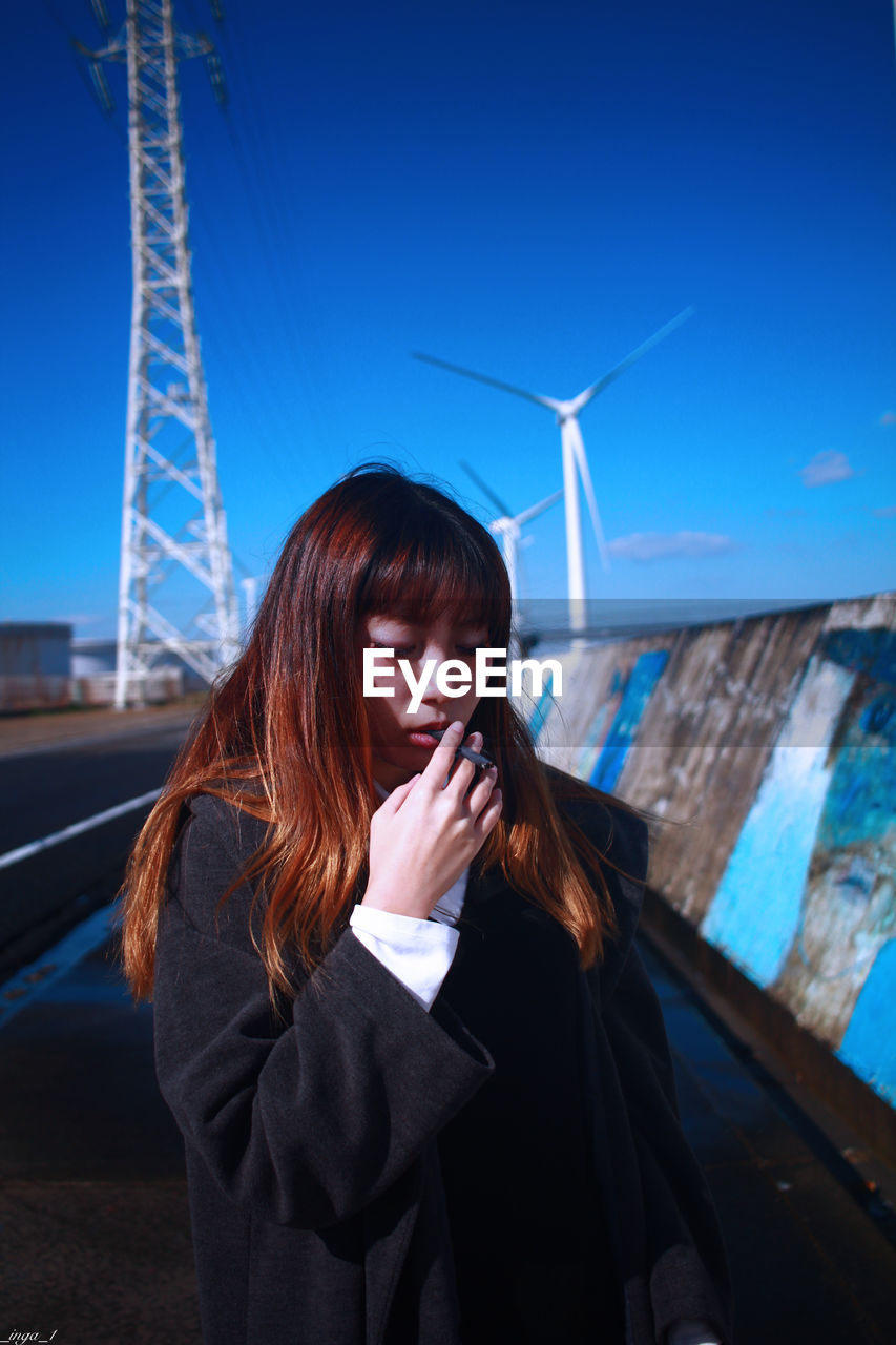 Beautiful young woman standing against sky