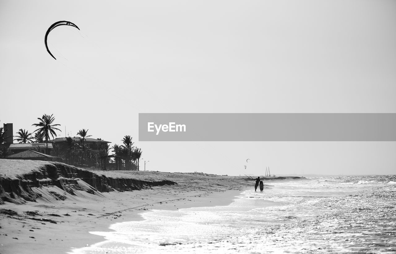 Man walking on beach against clear sky