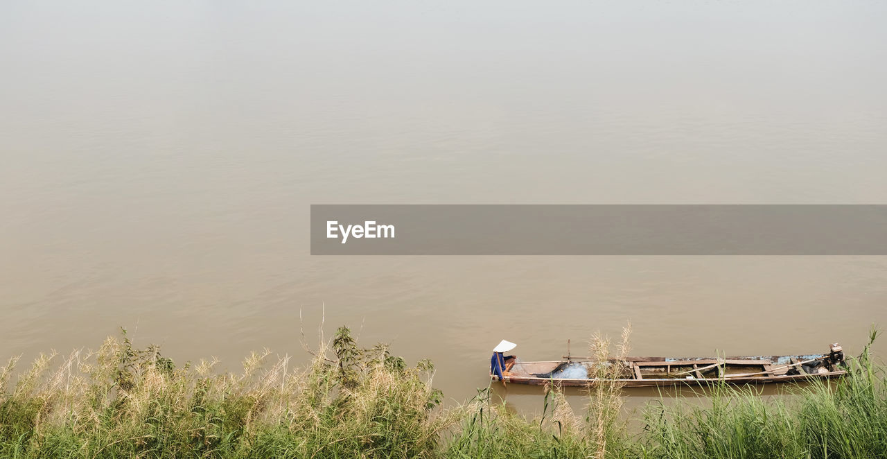 Fishermen take a wooden boat to find fish by the mekong river.