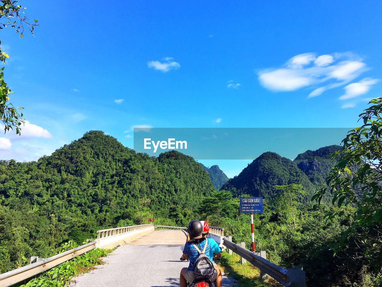 REAR VIEW OF MAN ON BICYCLE AGAINST MOUNTAIN