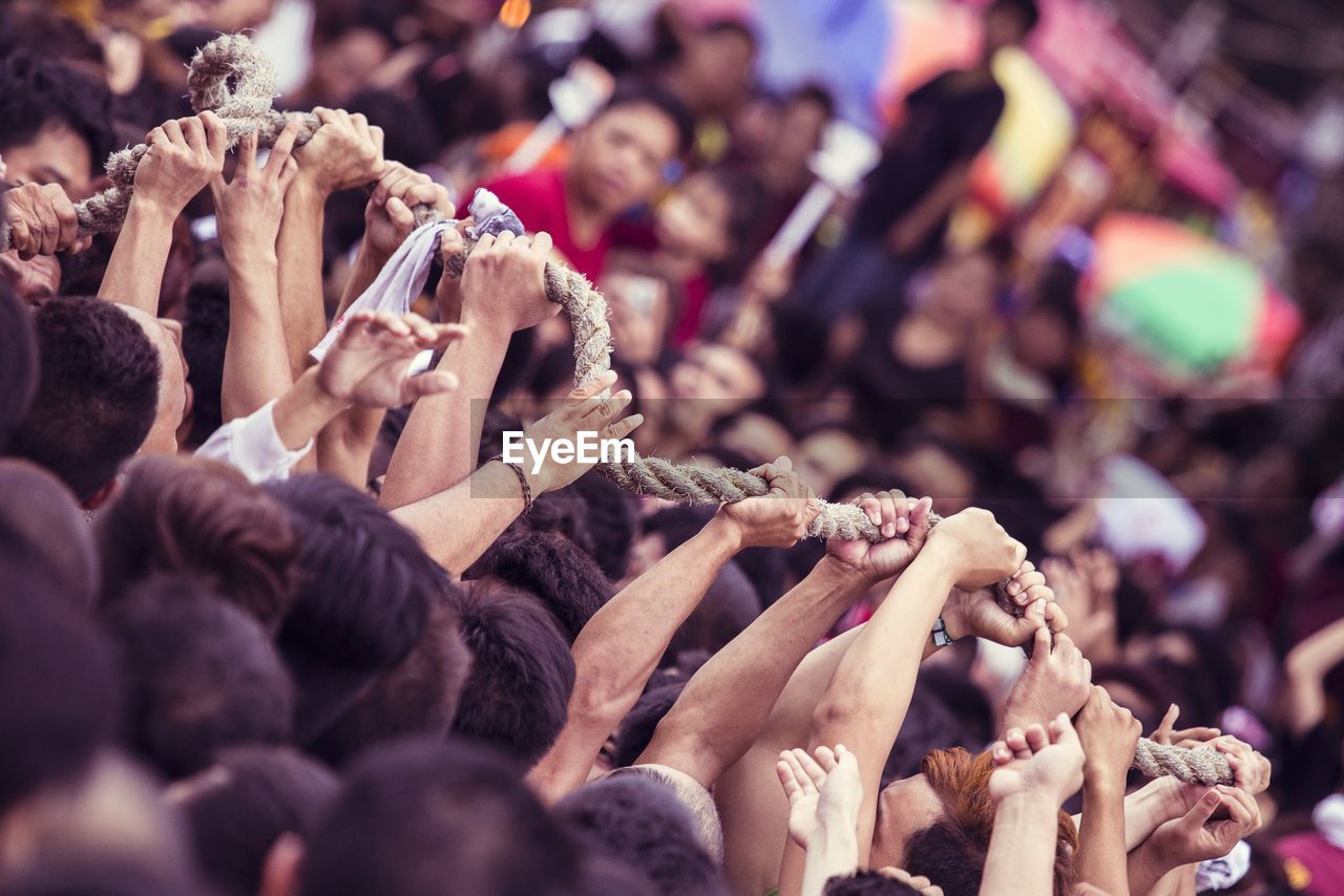 Close-up of hands holding rope in crowd