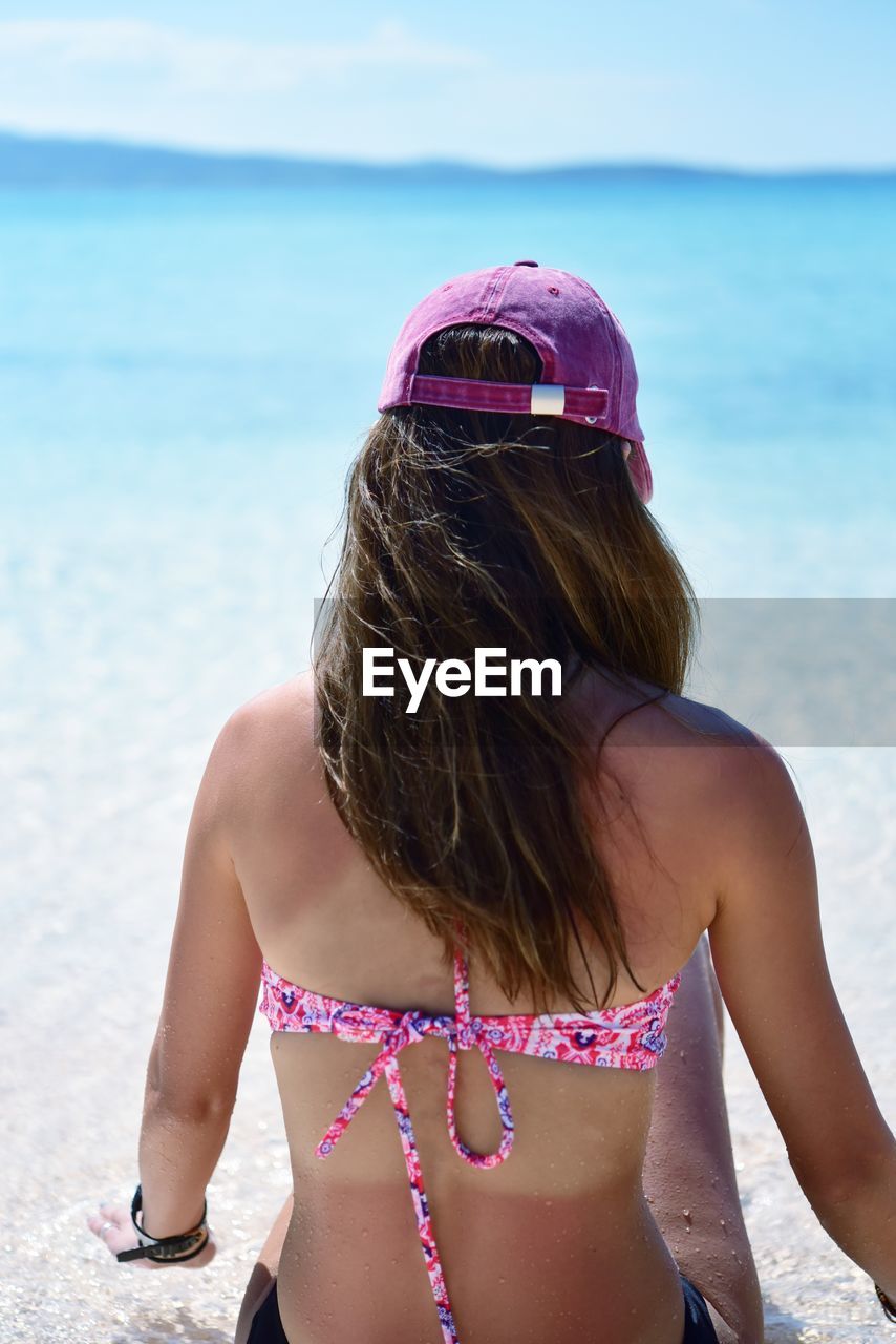 Rear view of woman at beach against sky