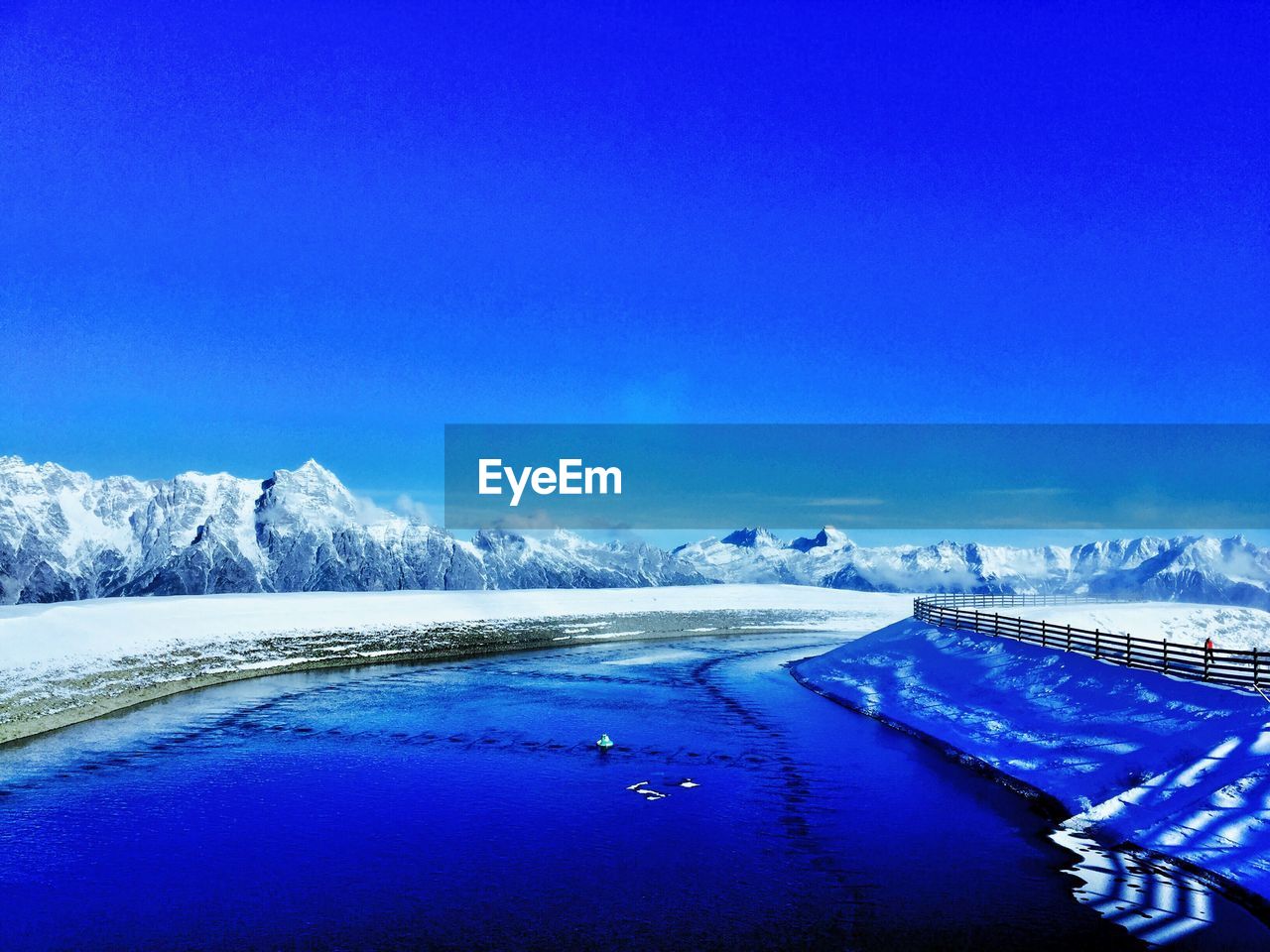Scenic view of river against blue sky during winter