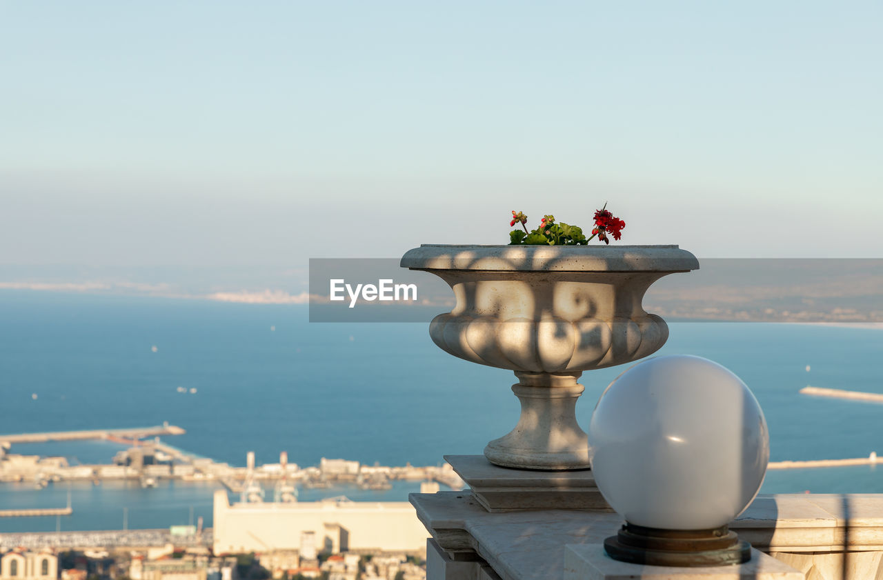 CLOSE-UP OF FLOWER POT ON SEA AGAINST SKY