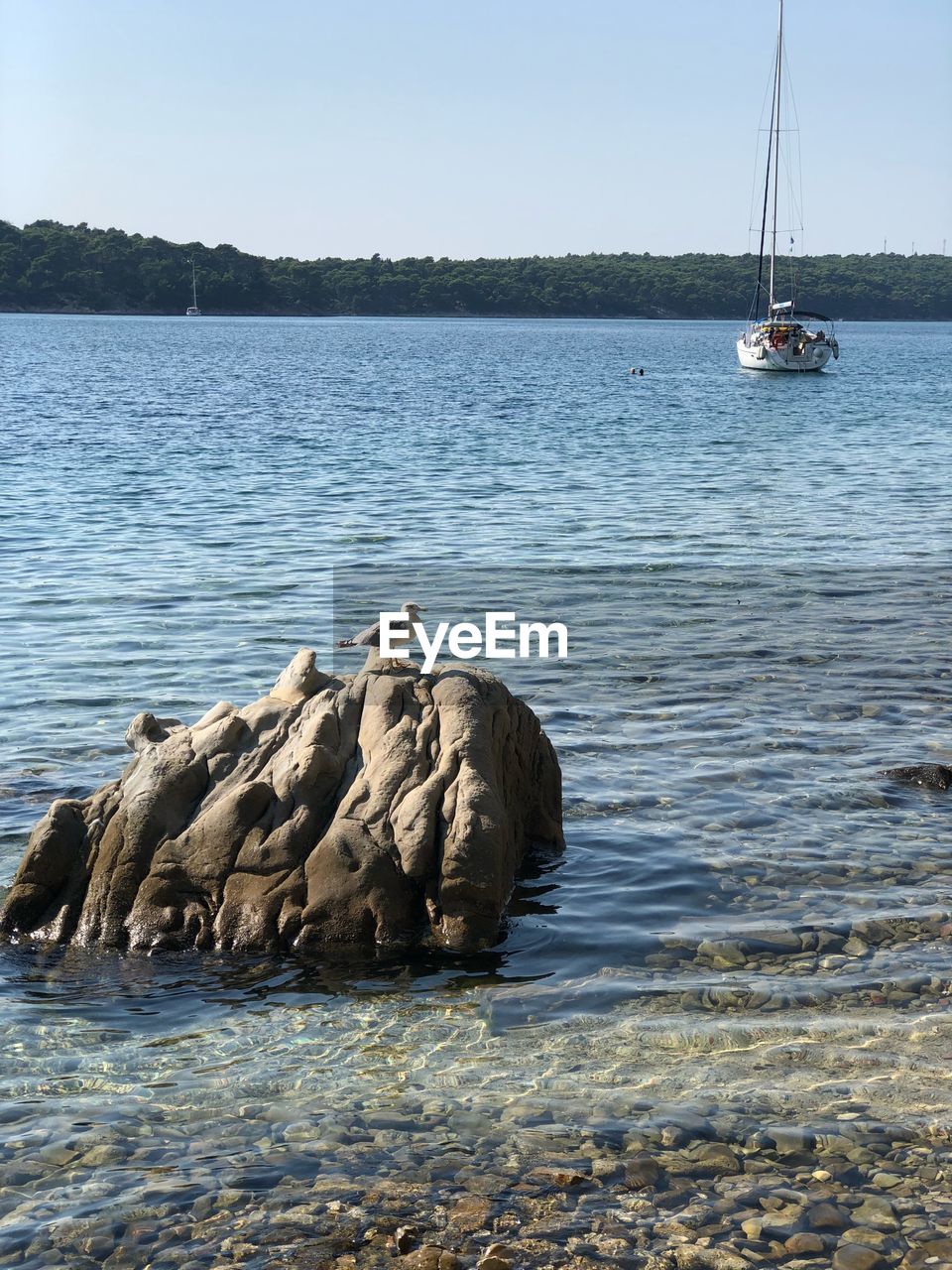 Sailboat on rock by sea against clear sky