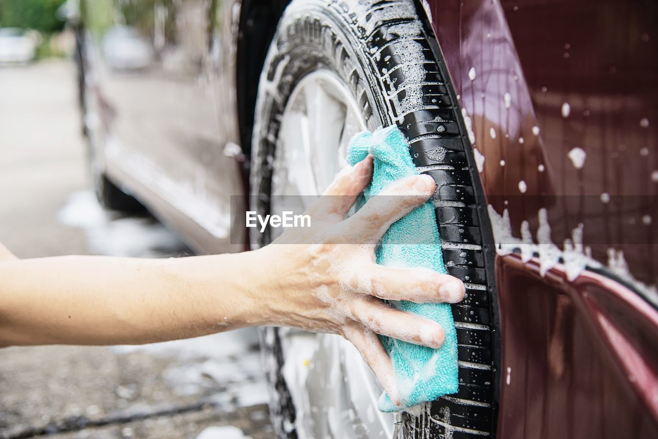 Cropped hands of man washing car tire