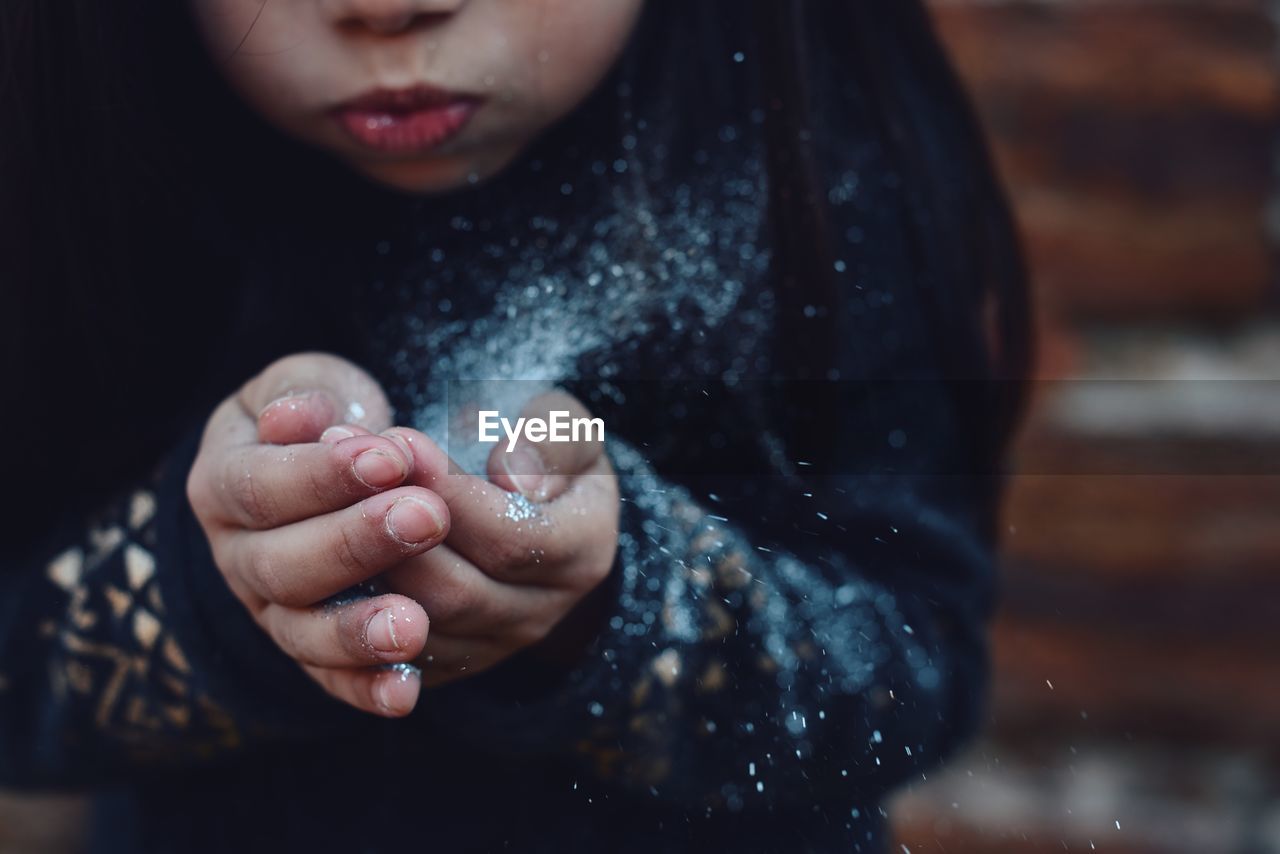 Close-up of girl blowing snow outdoors