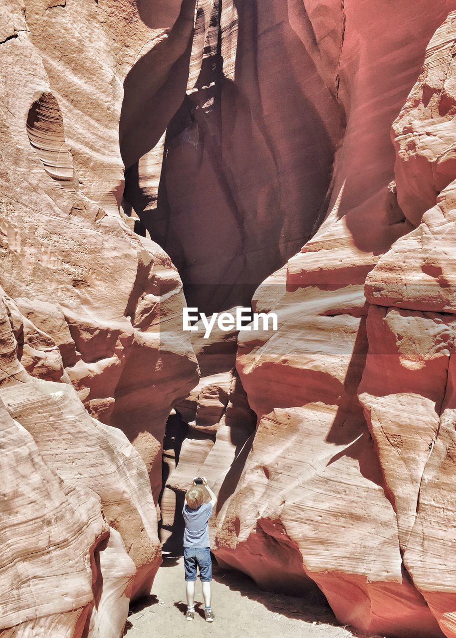 Rear view of boy photographing rock formation